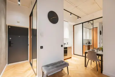 a living room with a chair and a clock on a wall at NG Charm in Old Town Apt w-Terrace & Netflix in Vilnius