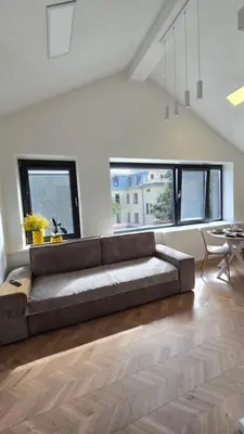 a large couch in a living room with windows at Santakos apartmentai in Kaunas