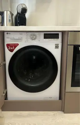 a white washing machine sitting in a kitchen at Cozy Šmozy Apartamentai in Šiauliai