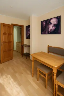 a dining room with a wooden table and a door at Home in Santariskes in Vilnius