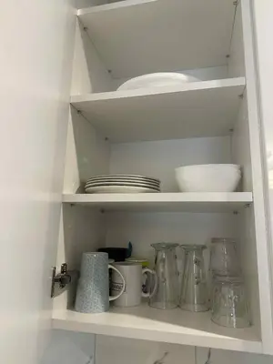 a kitchen shelf with dishes and utensils on it at Modern apartment with balcony in Užliedžiai