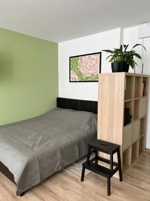 a bedroom with a bed and a black stool at DvaroStudio jaukus butas centre self-check-in in Šiauliai