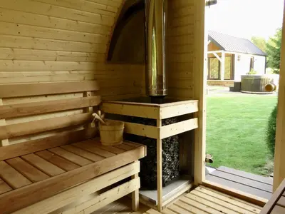 a wooden sauna with a wood stove in a yard at Gray House in Marijampolė