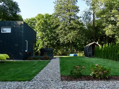 a garden with a black house and grass at Gray House in Marijampolė