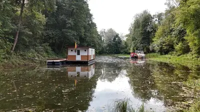 a small house on a boat in a river at Houseboat Vilnius in Vilnius