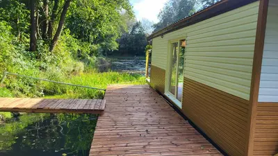 a wooden walkway next to a building next to a river at Houseboat Vilnius in Vilnius