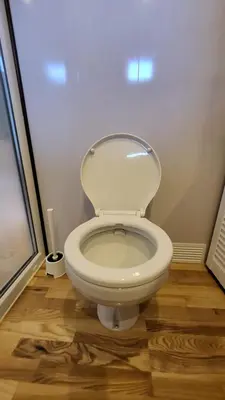 a white toilet in a bathroom with a wooden floor at Houseboat Vilnius in Vilnius