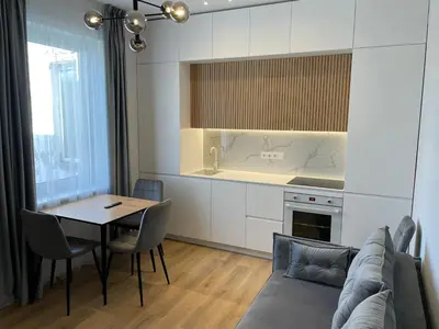 a living room with a couch and a table and a kitchen at Stylish Apartment 5 min from Kaunas Clinics in Kaunas