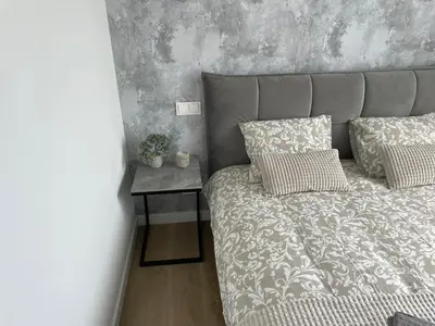a bed with two pillows and a nightstand with a bed sidx sidx sidx at Stylish Apartment 5 min from Kaunas Clinics in Kaunas