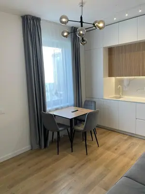 a dining room with a table and chairs and a kitchen at Stylish Apartment 5 min from Kaunas Clinics in Kaunas