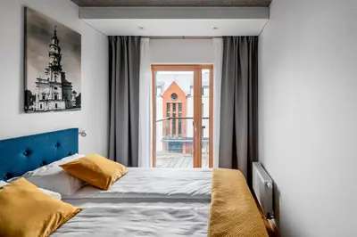 a bedroom with a bed and a large window at King Mindaugas Apartments in Kaunas
