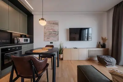 a kitchen and living room with a table and chairs at King Mindaugas Apartments in Kaunas