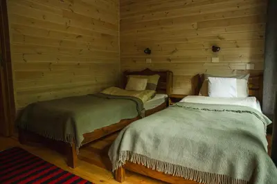 two beds in a room with wooden walls at Kaimo turizmo sodyba Kukarskė in Kiduliai