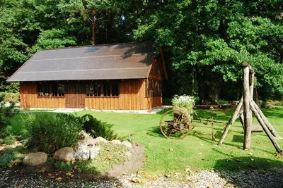 a wooden barn with a wheel in front of it at Kaimo turizmo sodyba Kukarskė in Kiduliai
