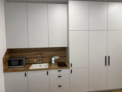 a kitchen with white cabinets and a sink and a microwave at poilsio ramybes oaze in VNO