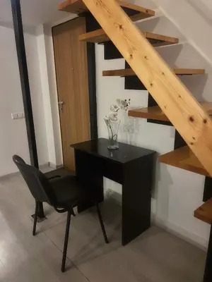 a black desk and a chair in a room with stairs at Tech City Apartments, Nr Vilnius Old Town in Vilnius