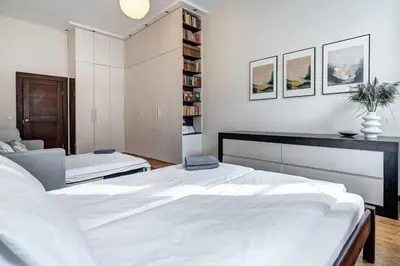 a white bedroom with two beds and a book shelf at Domillion Quiet 2bdr apt w panorama & balcony B83 in Vilnius