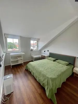 a bedroom with a green bed and two windows at Domillion 2bdr old town apt at Bazilijonai in Vilnius