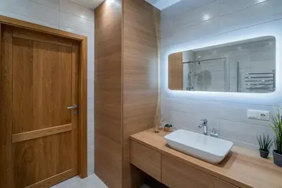 a bathroom with a sink and a wooden door at Domillion 1bdr lovely apt with parking &lift B9a4 in Vilnius