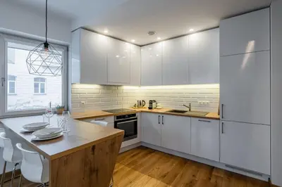 a kitchen with white cabinets and a table with chairs at Domillion 1bdr lovely apt with parking &lift B9a4 in Vilnius