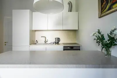 a kitchen with white cabinets and a vase of flowers at Domillion New City Hall Duplex D11C for 12 ppl in Vilnius
