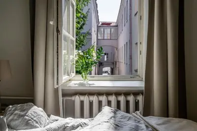 a bed in a bedroom with a window and a vase of flowers at Domillion New City Hall Duplex D11C for 12 ppl in Vilnius