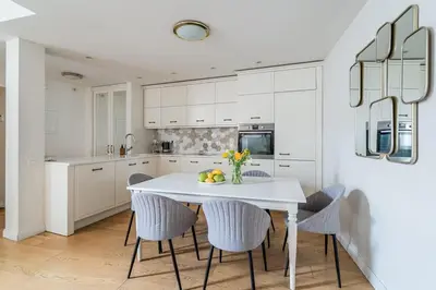 a white kitchen with a white table and chairs at Domillion 3bdr Huge Town Hall Luxury Apt AC D3948 in Vilnius