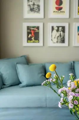 a living room with a blue couch with a vase of flowers at Domillion New Duplex 12ppl balconies free park N2A in Vilnius
