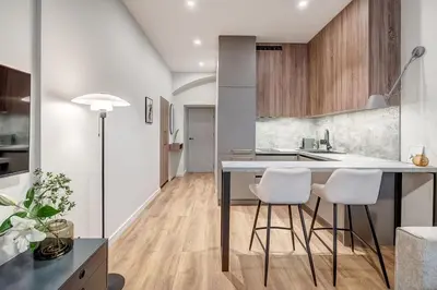 a kitchen with a table and two white stools at Domillion 1bdr Modern Old Town Retreat So1a in Vilnius
