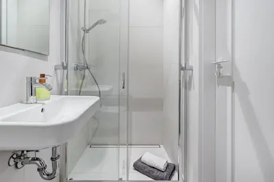 a white bathroom with a sink and a shower at Domillion Studio Modern Old Town Retreat So1b in Vilnius