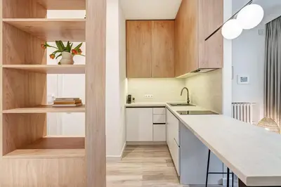 a kitchen with white counters and wooden cabinets at Domillion Studio Modern Old Town Retreat So1b in Vilnius