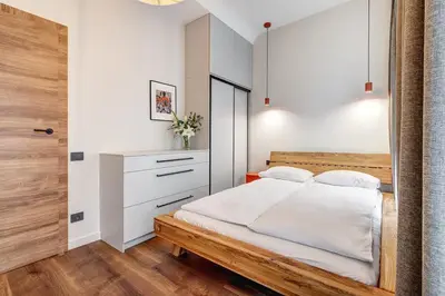 a bedroom with a wooden bed and a white wall at Domillion 2bdr Modern Old Town Retreat So1d in Vilnius