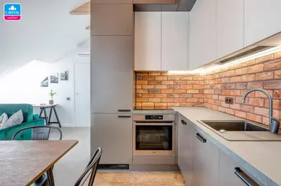 a kitchen with white cabinets and a brick wall at Domillion Pylimo Penthouse duplex apt 15ppl P36D in Vilnius