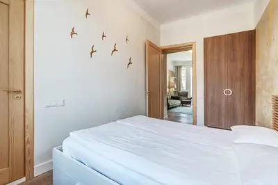 a bedroom with a white bed with birds on the wall at Domillion Penthouse Duplex w Terrace 18 ppl P36T in Vilnius