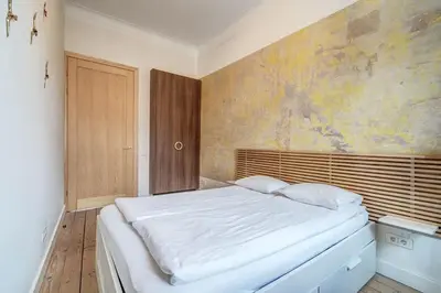 a bedroom with a white bed with a painting on the wall at Domillion Penthouse Duplex w Terrace 18 ppl P36T in Vilnius