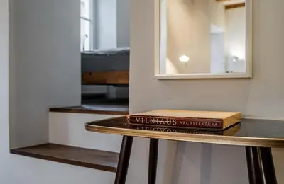 a book sitting on a table next to a mirror at Domillion 1bdr unique and warm Old Town apt Tr41 in Vilnius