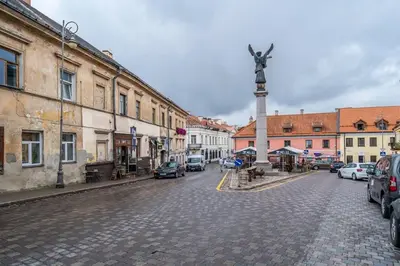 a cobblestone street with a statue of a cross on a pole at Domillion 1bdr brand-new Uzupis apt w free parking in Vilnius