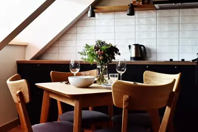 a table with a vase of flowers and wine glasses at Domillion New Modern Old town apt 16 ppl U2C1 in Vilnius