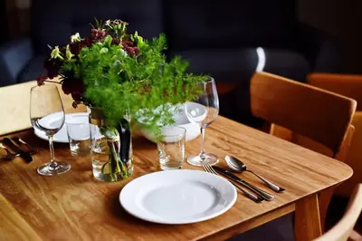 a table with a plate and glasses and a vase of flowers at Domillion New Modern Old town apt 14 ppl U2C2 in Vilnius
