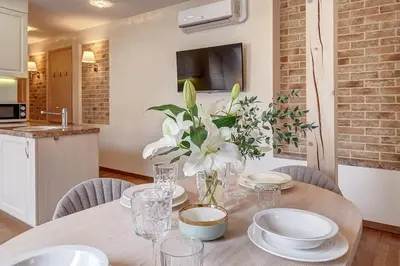 a table with white plates and flowers in a kitchen at Zemaitijos Versatile 12ppl Triplex in Vilnius
