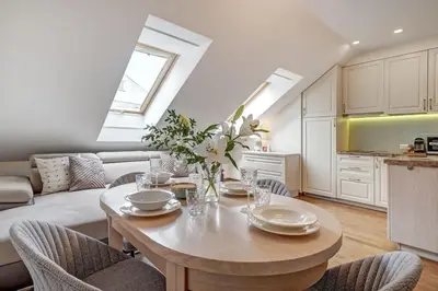 a living room with a table and a kitchen at Zemaitijos Versatile 12ppl Triplex in Vilnius