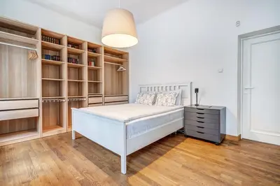 a bedroom with a white bed and wooden shelves at Domillion 2bdr Vilnius str antique apt Vl476 in Vilnius