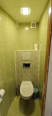 a bathroom with a toilet in a green tiled wall at Kosmonautų gatve in Panevėžys