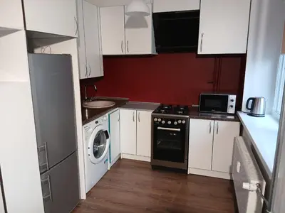 a kitchen with white cabinets and a washer and dryer at Alytus Studio 45 in Alytus