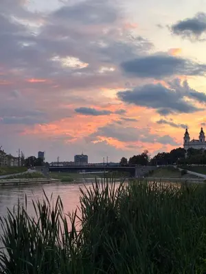 a sunset over a river with a train on a bridge at Old Town Riverside Haven in Vilnius