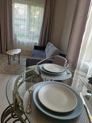 a living room with a glass table with plates on it at Vilmos studija in Šiauliai