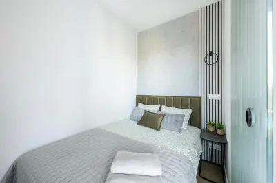 a white bedroom with a bed and a side table at Vilnius Central Modern Apartments Vepriai Street in Vilnius