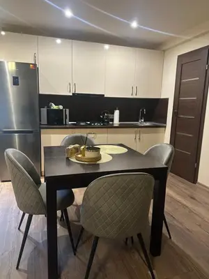 a kitchen with a table and chairs and a refrigerator at Projektuotojų Apartamentai in Panevėžys