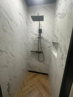 a bathroom with white marble walls and a lamp at Marių namai in Kaunas