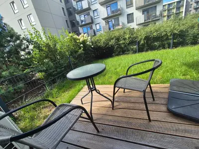 a table and chairs on a wooden deck with a table at Cozy 3-Room Flat by Twinsbet Arena & Ozas in Vilnius